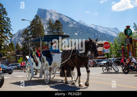 Banff, Alberta, Canada - June 20, 2018: Tourists are taking a tour on a hourse around the city. Stock Photo