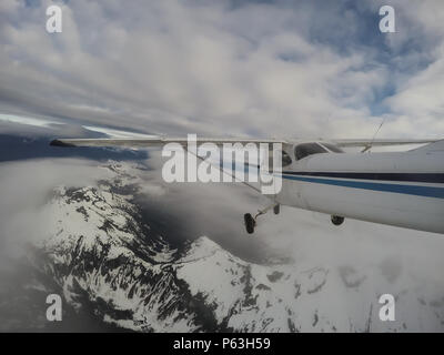 Airplane flying over the beautiful Canadian Mountain Landscape during a cloudy evening. Taken North of Vancouver, British Columbia, Canada. Stock Photo