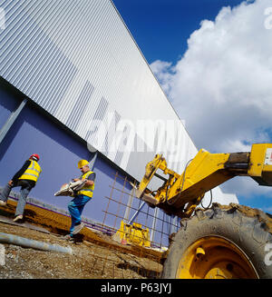 Construction workers and digger on site. Stock Photo