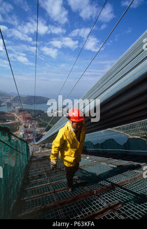 Worker climbs the suspended walkway beneath the cable being spun for the Tsing Ma suspension bridge in Hong Kong, China Stock Photo