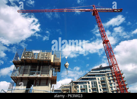 A tower crane lifts in concrete for a concrete core structure on new flats being built by St George alongside the Wandsworth bridge as part of its Tha Stock Photo