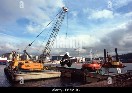 Grab dredging from a barge for the immersed tube tunnel crossing Oslo harbour-new Opera in the background Stock Photo