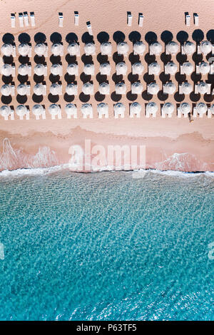 Aerial view of amazing turquoise sea with white umbrellas and sun loungers. Beautiful sunny summer day in Sardinia, Mediterranean sea, Italy. Stock Photo