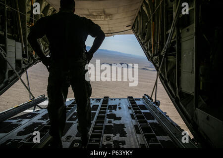 U.S. Marine Corps Sgt. Brian Gardner, jump master safety specialist with 2nd Marine Raider Battalion, Marine Raider Regiment, supervises parachute jumpers out of the back of a KC-130J Hercules during Weapons and Tactics Instructor (WTI) course 2-16 at Site 54, near Wellton, Ariz., April 15, 2016.  WTI is a seven week training event hosted by Marine Aviation Weapons and Tactics Squadron One (MAWTS-1) cadre. MAWTS-1 provides standardized advanced tactical training and certification of unit instructor qualifications to support Marine Aviation Training and Readiness and assists in developing and e Stock Photo