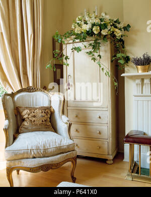 Georgian armchair and narrow painted cupboard with drawers in traditonal living room Stock Photo