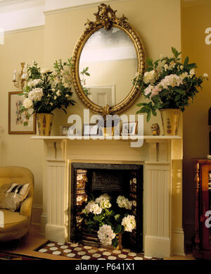 Antique mirror above cream fireplace in cream country living room with ...