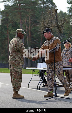 During the closing ceremony for Summer Shield XIII, Col. Martins Liberts (right), land force commander, Latvian army, presents a plaque to Spc. Paul Kariuki, a combat medic assigned to Headquarters and Headquarters Troop, 3rd Squadron, 2nd Cavalry Regiment, because he was chosen as one of the unit’s best soldiers throughout the exercise, April 29, at Adazi Military Base, Latvia. Soldiers from Latvia, Canada, Germany, Lithuania and the U.S. have been conducting a variety of training together during Summer Shield XIII, an annual two-week long interoperability training event in Latvia. Soldiers f Stock Photo