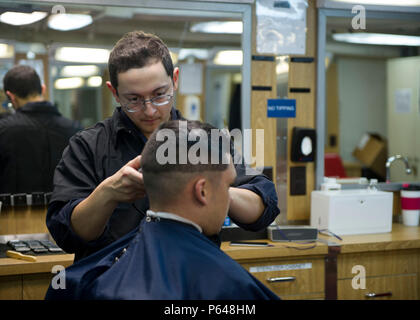 160419-N-VR008-016 SAN DIEGO (April 19, 2016) –Ship Serviceman Seaman Cristian Arzuaga gives Airman Donovan York a hair cut in the ship’s barber shop , on board the amphibious assault ship USS America (LHA 6). America is an aviation centric amphibious assault ship that supports Marine aviation requirements, from small-scale contingency operations of an expeditionary strike group, to forcible entry missions in major theaters of war. The ship is currently conducting maritime training operations off the coast of California. (U.S. Navy photo by Mass Communication Specialist 3rd Class Kyle Goldberg Stock Photo