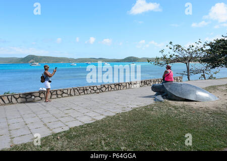 Tourist posing on a sea turtle sculpture on the Victoria Parade foreshore, Thursday Island, Torres Strait Islands, Far North Queensland, FNQ, QLD, Aus Stock Photo