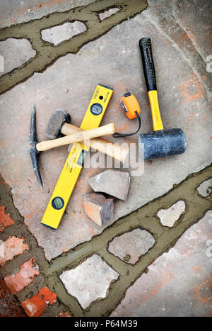 Builders tools amongst recently pointed joints awaiting brushing out on a patio laid with natural stone slabs, UK Stock Photo