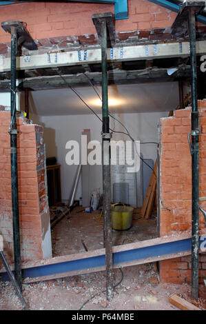 Acrow props with strong boys holding a supporting wall before a rsj is fitted to allow the enlargement of a wall opening Stock Photo