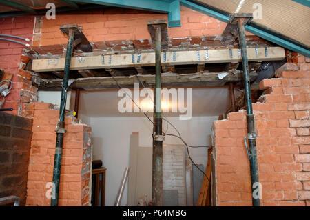 Acrow props with strong boys holding a supporting wall before a rsj is fitted to allow the enlargement of a wall opening Stock Photo