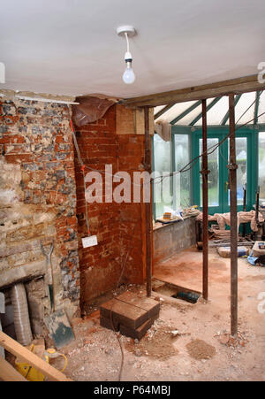 Acrow props with the load spread by a pair of scaffolding planks holding a supporting wall before a rsj is fitted to allow the enlargement of a wall o Stock Photo