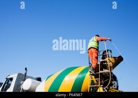 A concrete delivery man washes out the chute after pouring a mix of concrete. The cement industry is oneof the most carbon hungry on the planet. Stock Photo