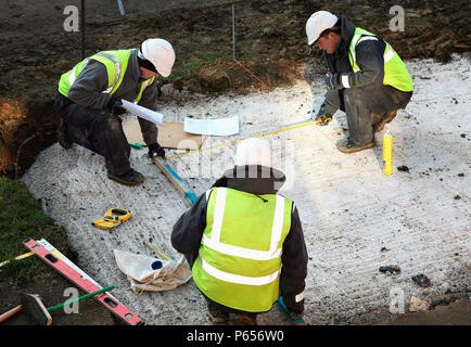 Construction workers using plans to mark floor Stock Photo