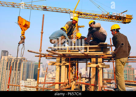 Construction workers discussing the installation of an air vent on the new HQ building of Chinese travel agent, CYTS, in Beijing Stock Photo