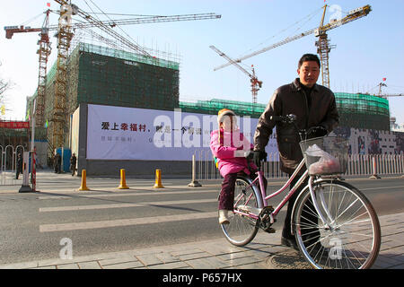 A Father and his daughter crossing a road next to a construction site in central Beijing Stock Photo