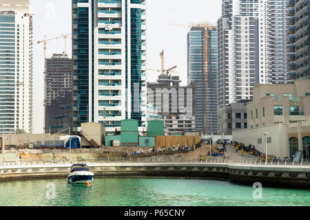 Immigrant construction workers rest below towers under construction. Dubai marina. Dubai Stock Photo