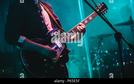 Guitarist on stage plays solo on electric guitar in cyan lights Stock Photo