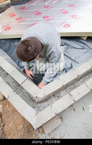 Builders lay under floor insulation into a house extension in Ambleside, UK. Stock Photo