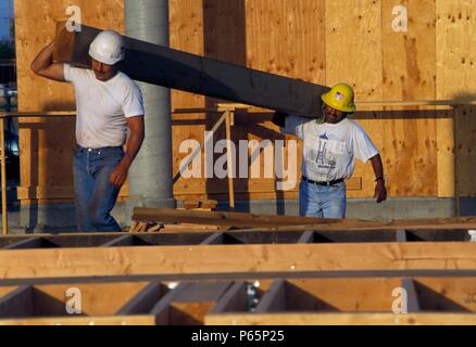 Two carpenters carrying large wooden beam Stock Photo