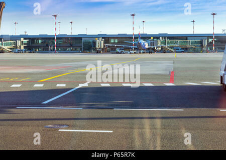 Passenger airplane at stationary terminal gates on airport runway, Marupe, Riga, Latvia. Road transport infrastructure of international airport. Aircr Stock Photo