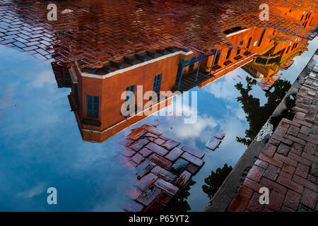 A restored Spanish colonial house is seen reflected in the puddle on cobbled street in the colonial walled city of Cartagena, Colombia. Stock Photo
