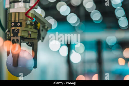 Closeup robot hand machine picking up white ball on bokeh blurred background. Use smart robot in manufacturing industry. Robotic tool in factory. Robo Stock Photo