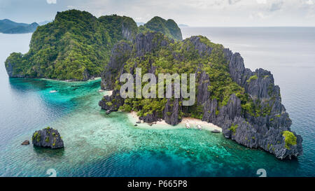 Aerial drone view of a tiny tropical island with beach, coral reef and sharp limestone cliffs (Shimizu Island, El Nido) Stock Photo