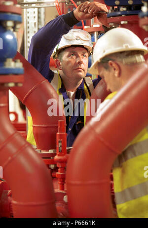 Two workers working as a team. Tightening valves using a spanner. Stock Photo