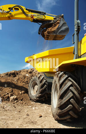 Excavator loading earth on to dump truck Stock Photo