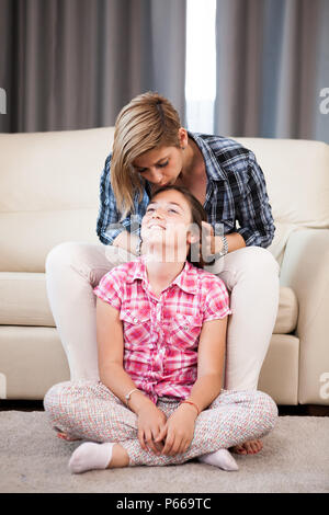 Beautiful mother kisses her daughter forehead Stock Photo