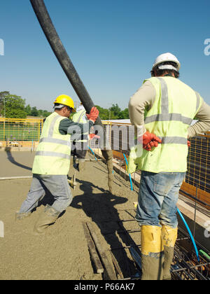 Men pouring concrete on to reinforced steel bar Stock Photo