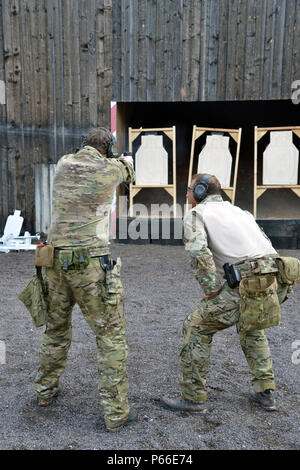 A U.S. Soldier assigned to 1st Battalion, 10th Special Forces Group (Airborne) monitors a fellow soldiers shooting technique during a M9 pistol range on Panzer Kaserne in Boeblingen, Germany, May 4, 2016. (U.S. Army photo by Visual Information Specialist Adam Sanders/RELEASED) Stock Photo