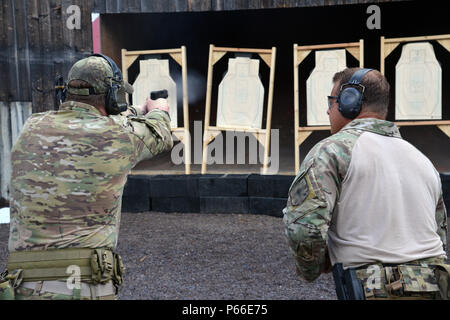 A U.S. Soldier assigned to 1st Battalion, 10th Special Forces Group (Airborne) monitors a fellow soldiers shooting technique during a M9 pistol range on Panzer Kaserne in Boeblingen, Germany, May 4, 2016. (U.S. Army photo by Visual Information Specialist Adam Sanders/RELEASED) Stock Photo