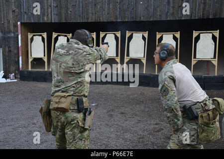 A U.S. Soldier assigned to 1st Battalion, 10th Special Forces Group (Airborne) monitors a fellow soldiers shooting technique during a M9 pistol range on Panzer Kaserne in Boeblingen, Germany, May 4, 2016. (U.S. Army photo by Visual Information Specialist Adam Sanders/RELEASED) Stock Photo