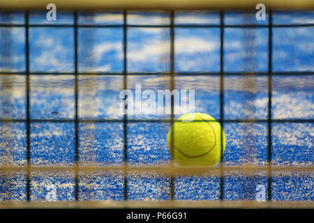 Tennis ball on a blue carpet floor next to the net. Empty copy space for Editor's text. Stock Photo