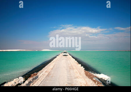 A pick up drives throgh the brines pools of the Salar de Atacama Stock Photo