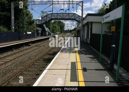 General platform view of Berkswell station, Warwickshire showing overhead electric catenary, waiting shelter and pedestrian footbridge. 2007 Stock Photo