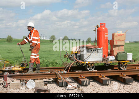 A trackworker with thermit welding equipment on a rail trolley as track renewal takes placenear to Peterborough. May 2005 Stock Photo