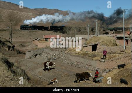 A typical village scene at Nandian on the Jing Peng pass in Inner Mongolia as a double headed freight climbs the final lap to the summit tunnel at Sha Stock Photo