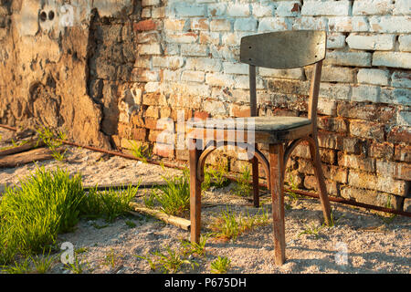 old wooden chair standing near the wall of a ruined house Stock Photo