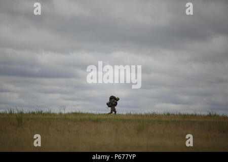 A Paratrooper from Fort Bragg, North Carolina walks off Sicily Drop Zone after performing a static line jump during the Saturday Proficiency Jump Program (SPJP) at Fort Bragg, North Carolina on May 21, 2016. The SPJP builds proficiency, experience, and confidence of individual Paratroopers, ensuring the XVIII Airborne Corps and 82nd Airborne Division remain ready for contingency response missions. (US Army Photo by Sgt. Tierney P. Curry)(Released) Stock Photo