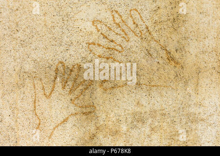 Drawing of two handprints on textured tan colored adobe wall Stock Photo