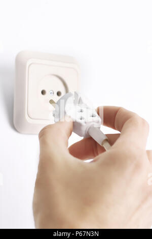 Hand inserting green electrical plug into outlet Stock Photo