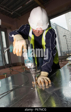Man drilling hole in metal panel, St Paul's Square, Old Hall Street, Liverpool, UK Stock Photo
