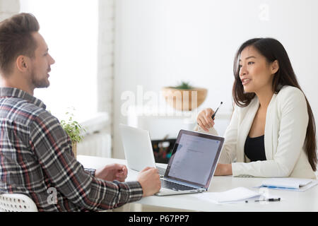 Colleagues friendly speaking while working at laptops in office Stock Photo