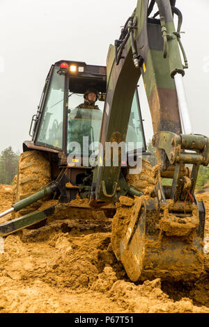 Lance Cpl. Austin Bradford, a heavy equipment operator with Marine Wing Support Squadron 171, engineer company, heavy equipment platoon, digs a fighting hole during exercise Thunder Horse 16.2 at the Japan Ground Self-Defense Force’s Haramura Maneuver Area in Hiroshima, Japan, May 12, 2016. The week-long exercise focused on reinforcing skills that Marines learned throughout their military occupational specialty schooling and during Marine Combat Training in order to maintain situational readiness. Heavy equipment operators and combat engineers dug fighting holes for defensive positions, provid Stock Photo