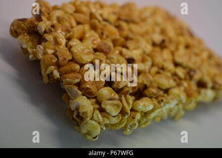 On a white paper background is located and placed from a delicious and sweet grilling of air corn kernels, popcorn with caramel Stock Photo