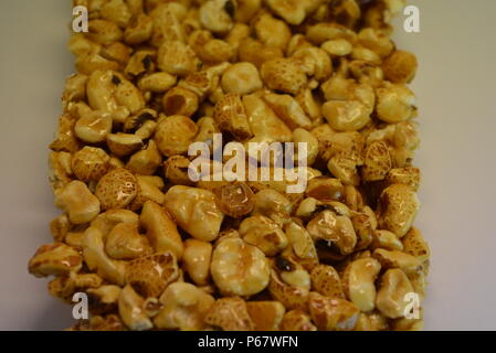 On a white paper background is located and placed from a delicious and sweet grilling of air corn kernels, popcorn with caramel Stock Photo
